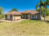 Charming single-story home boasts well-manicured lawn, mature trees, and neutral-toned exterior paint at 1941 Mathis Rd, St Cloud, FL 34771