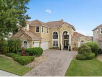 Elegant two-story home with a tile roof, arched windows, and a paver driveway at 2234 Callaway Ct, Davenport, FL 33837