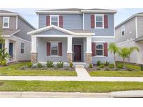 Charming two-story home featuring a covered porch with stone accents and a well-maintained lawn at 2877 Fitness St, Clermont, FL 34714