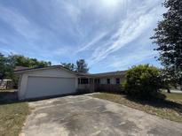 Single-story home with an attached two-car garage and a driveway in front, under a bright sky at 8 Emerald Way, Ocala, FL 34472