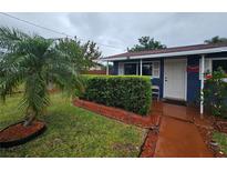 Charming single-story home boasts a well-manicured front yard with lush green landscaping, shrubs and palm tree at 1617 Emmett St, Kissimmee, FL 34741