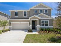 Charming two-story home featuring a two-car garage, stone accents, neutral colors, and well-maintained landscaping at 1690 Sugarbelle Cir, Mascotte, FL 34753