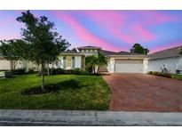 Charming single-story home with lush lawn, mature trees, and a brick driveway under a colorful, twilight sky at 789 Cielo Trl, Kissimmee, FL 34759