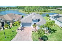 Beautiful aerial view of a home with lake view, solar panels, brick driveway, and lush landscaping at 363 Bella Cortina Dr, Kissimmee, FL 34759