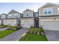 Street view of well-maintained townhomes with one car garages, paved driveways, and lush landscaping at 1177 Seaside Mist Trl, Kissimmee, FL 34747