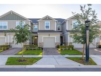 Picture of neutral townhomes with a one car garage, a paved driveway, and manicured landscaping at 1177 Seaside Mist Trl, Kissimmee, FL 34747