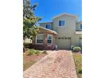 Inviting two-story townhome featuring stone accents, a one-car garage, and a brick-paved driveway at 2305 Chatham Place Dr, Orlando, FL 32824