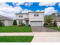 Charming two-story home boasts manicured lawn, brick-paved driveway, and a two-car garage at 5414 Log Grove Ln, Orlando, FL 32829