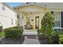 Inviting covered front porch with seating, decorative shrubbery, and brick walkway create a warm welcome at 6632 Pasturelands Pl, Winter Garden, FL 34787
