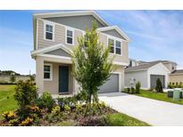 Two-story home featuring neutral siding, gray accents, an attached garage, and a well-manicured front yard at 816 Lake Dell Rd, Dundee, FL 33838