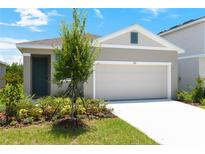 Charming single-story home with a two-car garage, beautifully landscaped front yard, and neutral-toned exterior at 828 Lake Dell Rd, Dundee, FL 33838