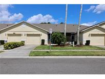Charming villa-style home with a well-maintained lawn and a beige exterior at 127 Club Villas Ln, Kissimmee, FL 34744