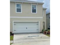 Beige two-story home featuring a two-car garage, manicured landscaping, and neutral color palette at 167 Eagleview Loop, Davenport, FL 33837