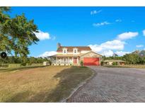 Stunning two-story home boasts a charming front porch, red garage door, and brick-paved driveway at 3255 Tucker Ave, St Cloud, FL 34772