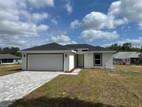 Charming single-story home featuring a two-car garage, and a well-manicured lawn on a sunny day at 68 Water Track Loop, Ocala, FL 34472