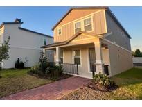 Charming two-story home featuring a welcoming front porch, landscaped yard, and neutral color palette at 12253 S Bracco St, Winter Garden, FL 34787
