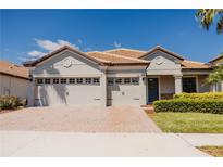 Charming single-story home with a paver driveway and a two-car garage and a blue sky backdrop at 1302 Moss Creek Ln, Davenport, FL 33896