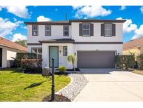 Charming two-story home featuring a well-maintained lawn, a two car garage, and an inviting entrance at 227 Sand Ridge Drive, Davenport, FL 33896