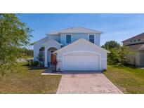 Charming two-story home featuring a white exterior, brick driveway, and well-maintained landscaping at 2764 Patrician Cir, Kissimmee, FL 34746