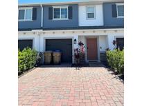 Charming townhome featuring a brick-paved driveway and an attached one-car garage at 2883 Narcoossee Commons Way, St Cloud, FL 34771