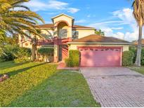Charming home boasts a well-maintained lawn, arched entry, and a pink two-car garage at 638 Kangaroo Dr, Poinciana, FL 34759
