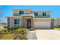 Contemporary two-story home featuring a two-car garage, stone accents and manicured landscaping at 1003 Sugarwood St, Davenport, FL 33837