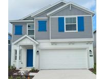 Charming two-story home features a gray facade with bright blue shutters and a white garage door at 1796 Foreman Rd, Eagle Lake, FL 33839