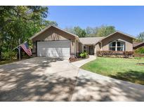 Charming home featuring a two-car garage, American flag, and beautifully landscaped front yard at 2074 King Richards Ct, Orange City, FL 32763