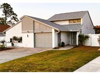 Charming home featuring a gray roof, an attached garage, and a well-manicured lawn at 2615 Autumn Green Dr, Orlando, FL 32822