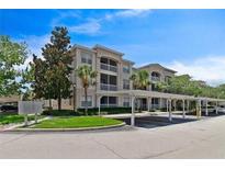 Lovely condo complex with covered parking, lush landscaping, and light stucco exterior at 3025 Greystone Loop # 302, Kissimmee, FL 34741