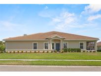Charming one-story home featuring a well-manicured lawn, neutral stucco, and a classic tile roof at 1000 Blackwolf Run Rd, Davenport, FL 33896