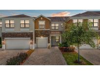 Inviting townhome with brick driveway, two-car garage, and well-maintained landscaping at 1809 Portofino Meadows Blvd, Orlando, FL 32824