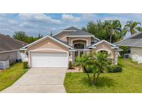 Charming home with a well-manicured lawn, palm trees, and a two-car garage, offering curb appeal at 301 Wingdale Way, Davenport, FL 33897