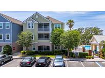 Two-story condo features a screened balcony, palm trees, and dedicated parking spots at 3344 Corona Village Way # 207, Orlando, FL 32835