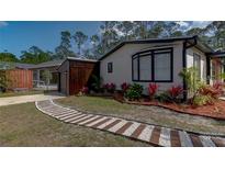 Charming single-story home with a stone and wood path, vibrant landscaping, and a detached garage at 3669 General Marshall Rd, Daytona Beach, FL 32124