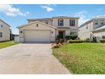 Charming two-story home features a well-manicured lawn and an attached two-car garage at 410 Canna Dr, Davenport, FL 33897
