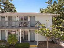 Charming two-story condo featuring gray paint, a balcony, and a well-maintained front yard with mature landscaping at 4820 Conway Rd # 130, Orlando, FL 32812