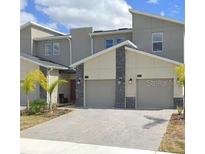 A contemporary townhome with attached two-car garage, stone accents, and manicured landscaping at 637 Ocean Course Ave, Davenport, FL 33896