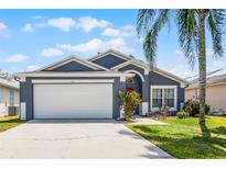 Charming single-Gathering home featuring a two-car garage, well-maintained lawn, and a beautiful palm tree in the front yard at 829 Clear Creek Cir, Clermont, FL 34714