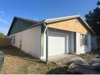 View of attached one car garage of single story home with white door and stucco siding, surrounded by lawn at 930 Buttercup Dr, Lakeland, FL 33801