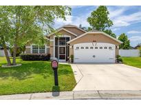 Charming one-story home featuring a well-manicured lawn and an attached two-car garage at 239 King George Dr, Davenport, FL 33837