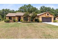 Charming one-story home with a well-manicured lawn, mature trees, and a tile roof at 2560 Greenwood Dr, Kissimmee, FL 34744