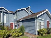 Charming two-story townhome featuring a blue exterior, well-maintained landscaping and a bright red front door at 914 Caribbean Dr, Davenport, FL 33897