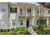Charming townhouse featuring a balcony, black shutters, lush landscaping, and a welcoming entrance at 1303 Artisan E Ave, Celebration, FL 34747