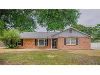 Charming brick home featuring black shutters and a well-maintained front yard, shaded by a mature tree at 1700 E Clinton Dr, St Cloud, FL 34769