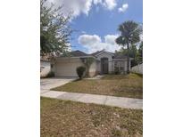 Charming single-story home features a two-car garage, palm tree and a well-maintained lawn at 1948 Bridgeview Cir, Orlando, FL 32824