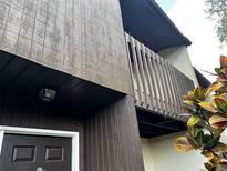 Low angle view of a two-story exterior featuring stained wood and a balcony with paneled rails at 2659 Crown Ct # 11, Kissimmee, FL 34741