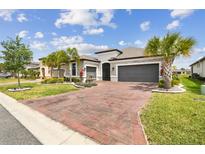 Charming home boasts a well-manicured lawn, palm trees, brick driveway, and a two-car garage at 433 Via Abruzzi St, Kissimmee, FL 34759