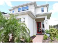 Bright home featuring a red front door, lush landscaping, and modern architectural details at 6617 Harper Way, Harmony, FL 34773