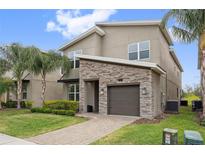 Charming two-story home featuring a stone accent facade, well-manicured lawn, and a paver driveway at 721 Drop Shot Dr, Davenport, FL 33896